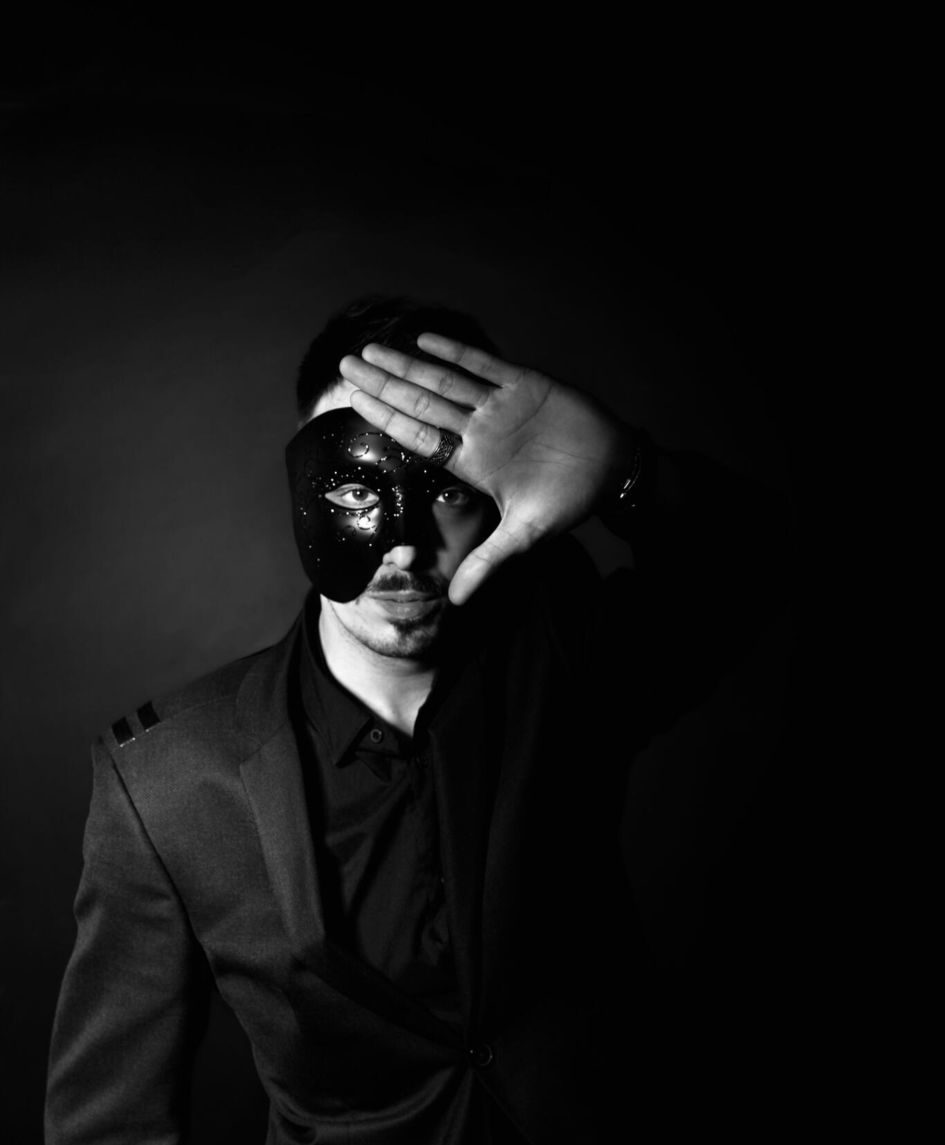 Black Mask – Marketing bez iluzji Mężczyzna w czarnej masce odsłaniający jedno oko dłonią – symbol obnażania marketingowych iluzji